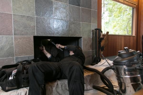 Fireplace contractor sweeping chimney