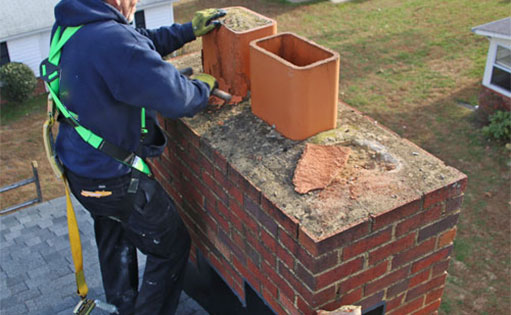 Harnessed man fixing terracotta chimney